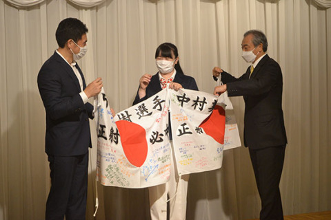 壮行会で、ハードオフコーポレーションの山本会長（右）と山本太郎社長（左）から「正射」「必勝」の文字と寄せ書きが書かれた日章旗を贈られ、笑顔を見せる中村選手