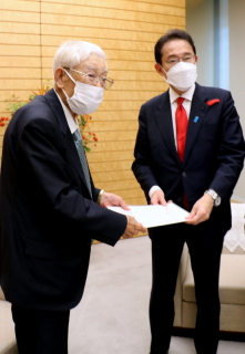 岸田首相（右）に要望書を手渡す新田会長＝15日午後零時半すぎ、首相官邸で