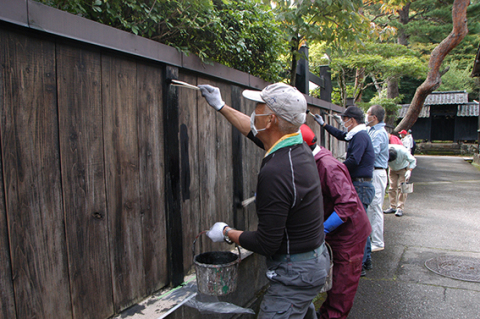 塀の塗り替えボランティアを行う手向地区民