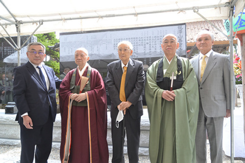 建立、除幕された奉賛会顕彰碑前で記念写真に納まる新田最高顧問（中央）と五十嵐住職（左から2人目）