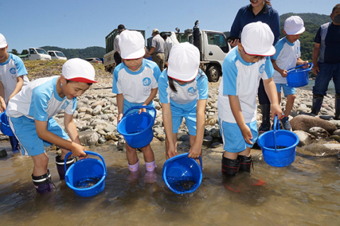 稚魚を放流する立川小2年生児童ら