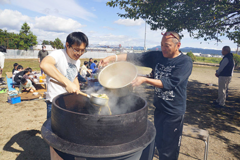 大釜で調理した芋煮を鍋に移す住民ら