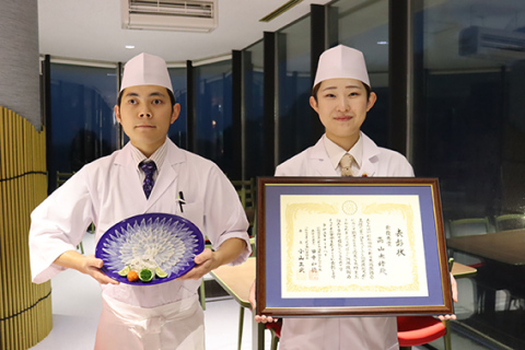 最優秀賞の表彰状を持つ高山さん（右）と、丸フグの技術大会で頂点に立った村上さん。自ら手掛けた繊細で美しいふぐ刺しを披露