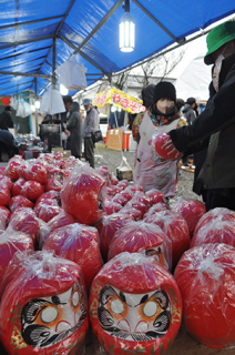 師走恒例の「だるま祭り」が開かれ、家族連れなどが縁起物のだるまを買い求めた＝17日午前