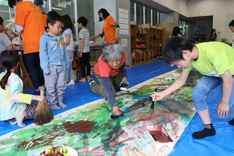 子どもと一緒に大きな木の絵を描く荒井さん＝19日、鶴岡アートフォーラム