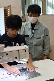 工業用ミシンを使って縫製加工を体験＝三洋のブース