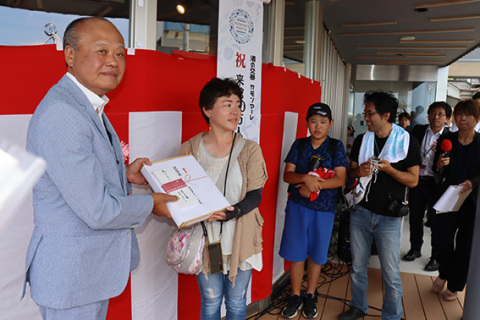 オープン1周年で来館者10万人を達成し、記念のセレモニーが行われた＝鶴岡市加茂・渚の交番カモンマーレ