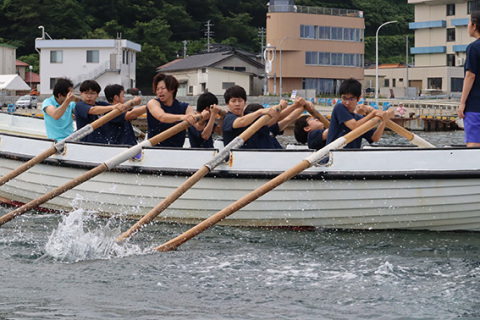 レースで息を合わせてオールをこぐ生徒たち