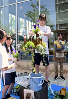 井上さん（右）の指導で次々と花を植え替える生徒たち