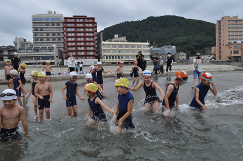 歓声を上げながら海へ入る湯野浜小の児童たち＝鶴岡市の湯野浜海水浴場