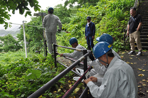 避難路の手すりにＬＥＤ照明を設置する生徒たち