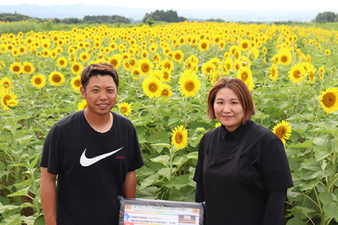 大輪の花が咲き誇る「月山高原ひまわり畑」と齋藤夫妻