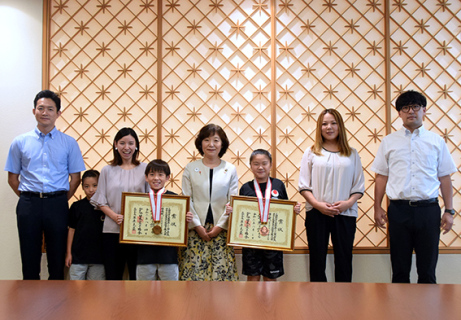 矢口市長（中央）を囲む本田君（左から4人目）と今井さん（同6人目）。右は指導者の齋藤さん