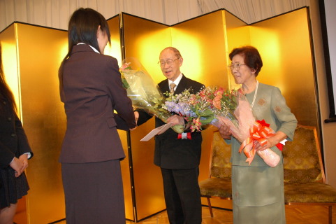 花束を受ける山崎氏とみよ夫人