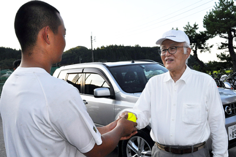 蛍光色が施された再生ボールを手渡す平田さん（右）