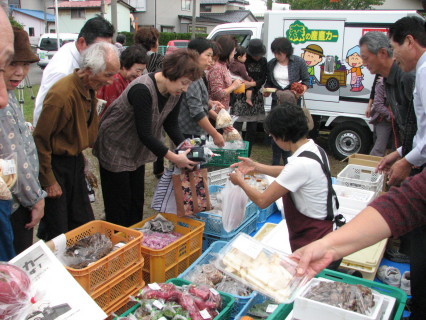 産直カー「あさひ号」が運んできた山の幸を買い求める住民たち＝鶴岡市の長者町西公園