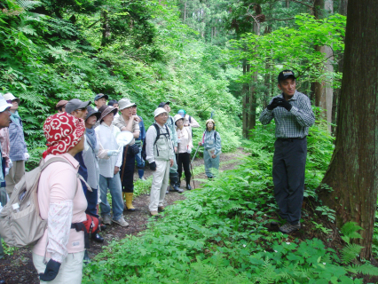 三瀬地区の水源林コースで地元の加藤さん（右）の説明を聞く参加者たち