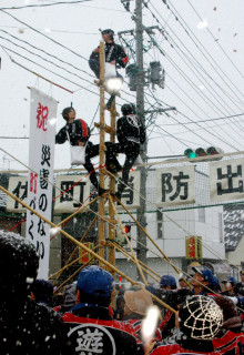 災害のない町を目指しはしごの上からもちをまく団員たち