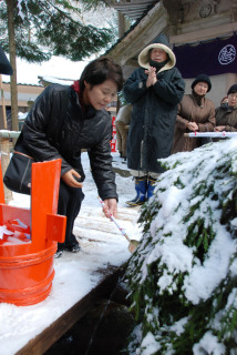 雪が降り積もった竜王沢から水をくみ、無病息災などを祈願する参列者たち＝貝喰池奥の院