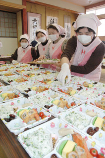 高齢者宅に配食する弁当作りの準備作業に精を出す会員たち