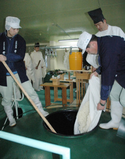 麹などを酒造タンクに入れる蔵人たち