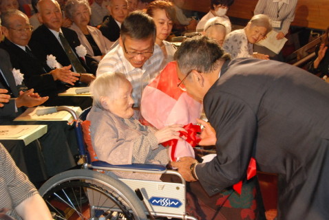 長寿を祝い101歳以上の出席者に花束を贈る榎本市長（右）