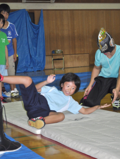 子供たちがプロレスラーから前転や前回り受け身の正しい方法を教えてもらった