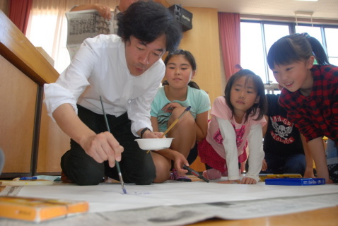 土田さん（左）がイラストを描く様子に子供たちは興味津々