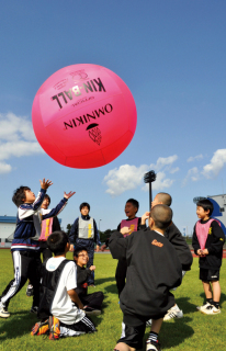 青空が広がる中、芝生の上で子供たちが歓声を上げながら「キンボール」に挑戦＝鶴岡市小真木原陸上競技場