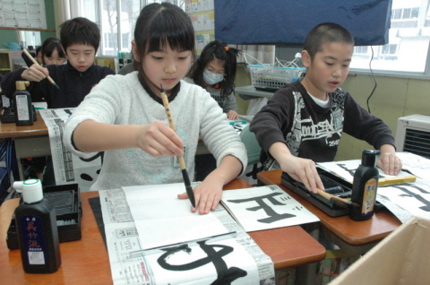 真剣な表情で新年の書き初めに挑戦する児童たち＝6日、朝六小