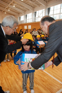 園児たちが大きなランドセルと黄色の帽子を受け取った＝7日、立川小