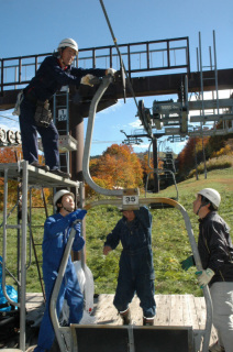 スキー場オープンを前にリフトの取り付け作業を行う従業員たち＝5日、鶴岡市湯殿山スキー場