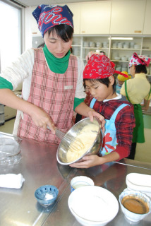 協力してケーキ用の卵黄を混ぜる親子