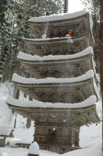 羽黒山五重塔の屋根の上から積もった雪を落とす職員たち＝30日午前