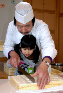 長い包丁を使ってケーキを切り分ける園児