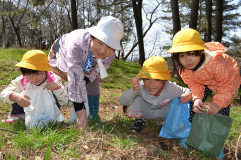 仲良くヨモギを摘む園児とお年寄りたち