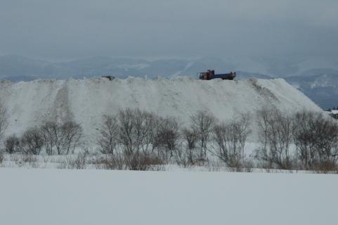 捨てられた雪が山脈のようになっている三川橋上流の赤川右岸の排雪場