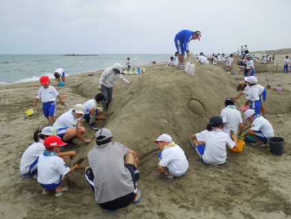 全校児童で力を合わせ恒例の砂のアートに挑んだ