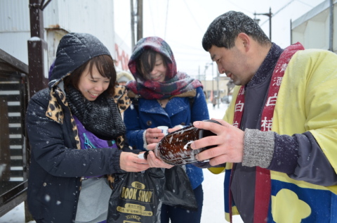 雪が降る中、列をつくる参加者にぬる燗が振る舞われた＝羽根田酒造