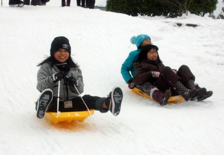 雪の感触を味わいながらそり滑りを楽しみ歓声をあげる沖縄の児童