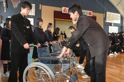 2年生の修学旅行隊に3年生（右）が車いすを託した