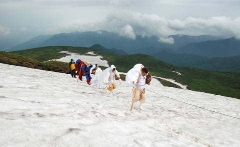 風にあおられながら県内外の参拝客が思い思いに山頂を目指した＝1日午前