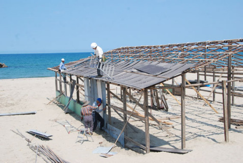 晴天の下、作業員たちが浜茶屋の建設作業を進めた＝9日、湯野浜海岸