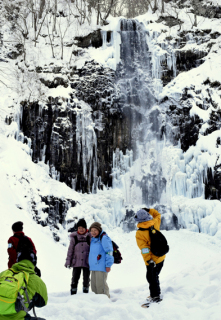 壮大な滝の姿をバックに記念写真を撮る参加者たち