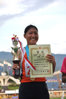 表彰台で賞状とトロフィーを手に、笑顔を見せる齋藤選手