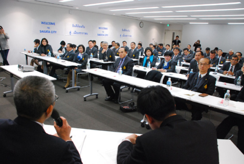 酒田市役所で永田部長（手前左）から日本の自治制度などについて説明を聞くニティセネ長官（中央）ら＝4日午後3時半すぎ