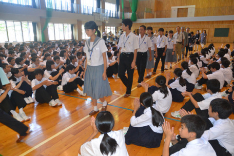 1200キロ離れた兄弟校の鶴岡二中を訪れ、拍手で歓迎交流会に迎えられる武中の生徒たち