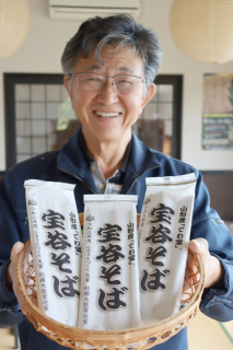 「多くの人に食べてほしい」と「でわ宝」の乾麺を持つ本間組合長