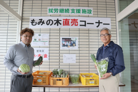 「ミニ産直」で野菜を持つ鶴峰産業の丸山社長(左)ともみ木の佐藤事業部長