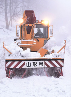 ロータリー除雪車がエンジン音を響かせながら雪を山間に吹き飛ばした